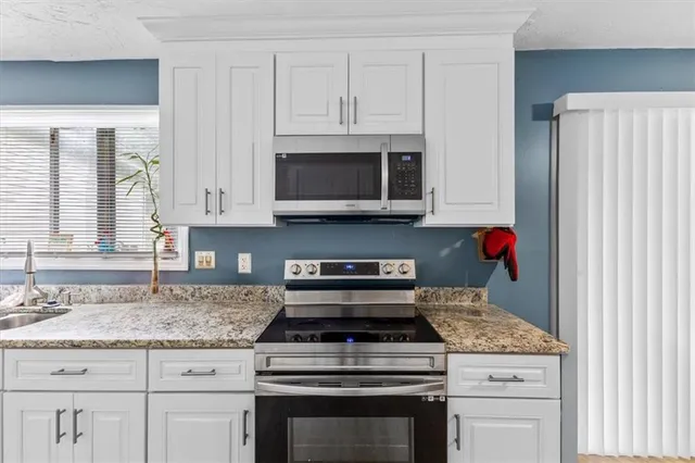 a kitchen with stainless steel appliances kitchen island granite countertop a table chairs and a refrigerator