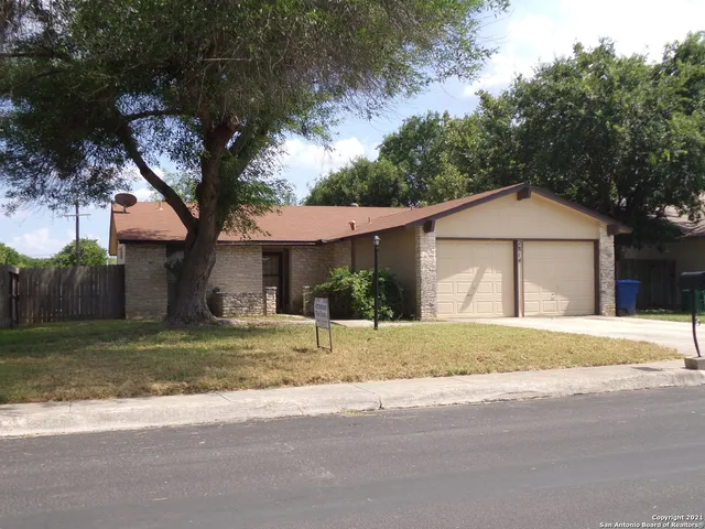 a view of a house with a yard and large tree