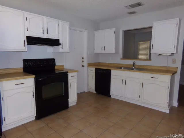 a kitchen with white cabinets and black appliances