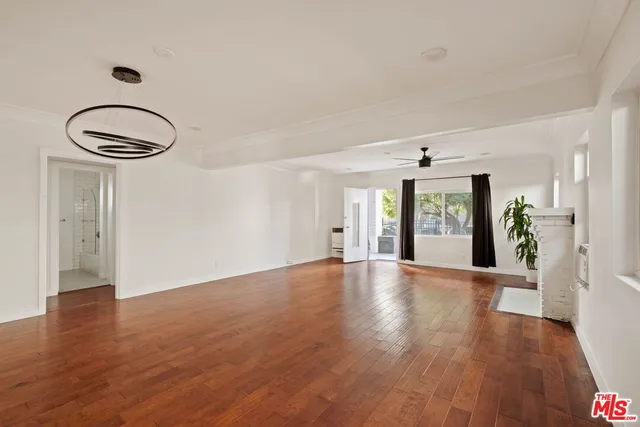 a view of an empty room with window and wooden floor