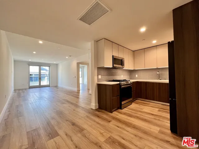 a kitchen with stainless steel appliances kitchen island granite countertop a refrigerator and a stove top oven