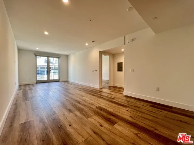 a view of an empty room with window and wooden floor