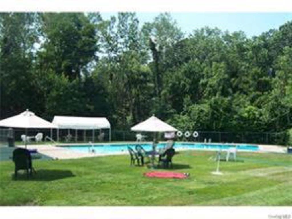 1 Secora Road, Unit B17 Monsey, NY 10952 - Photo 9 of 9 a view of a swimming pool with a table and chairs under an umbrella