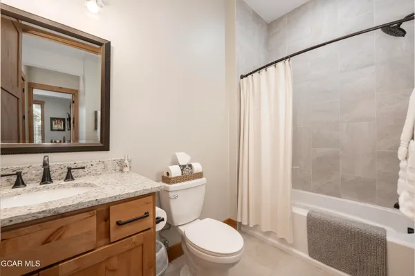 a bathroom with a granite countertop sink toilet mirror and a bathtub