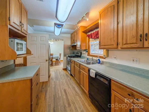 a kitchen with stainless steel appliances a stove a sink dishwasher and cabinets with wooden floor