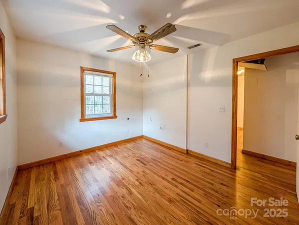 an empty room with wooden floor fan and windows