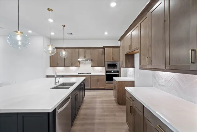 a large kitchen with kitchen island a sink a counter top space stainless steel appliances and cabinets