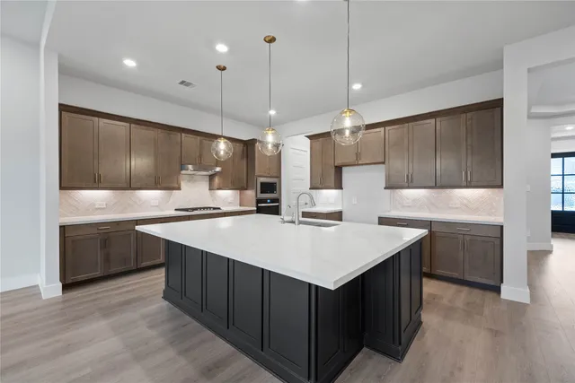 a kitchen with kitchen island a sink stainless steel appliances and cabinets