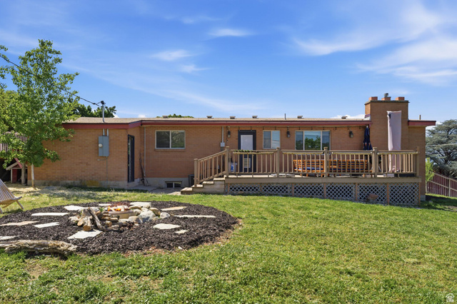 935 900 North Bountiful, UT 84010 - Photo 36 of 46 Back of house with a deck, brick siding, a chimney, a fire pit, and a yard