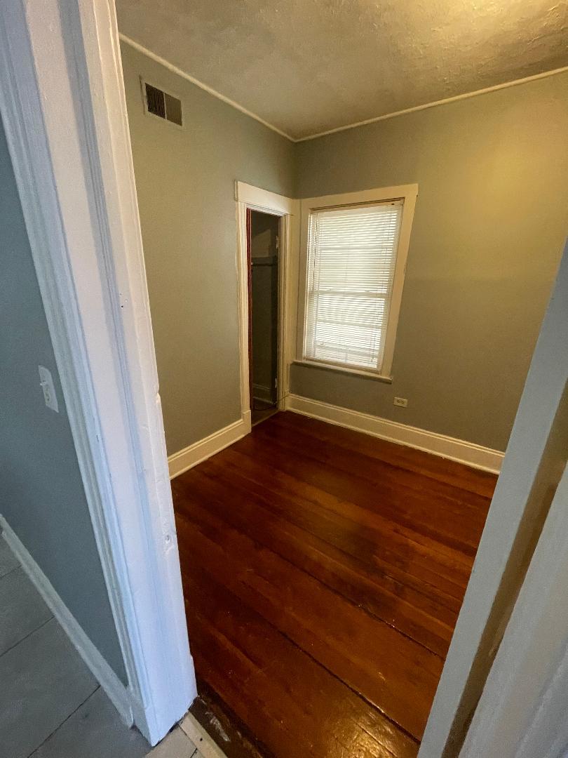 8136 South Exchange Avenue, Unit 2 Chicago, IL 60617 - Photo 3 of 8 a view of an empty room with wooden floor and a window