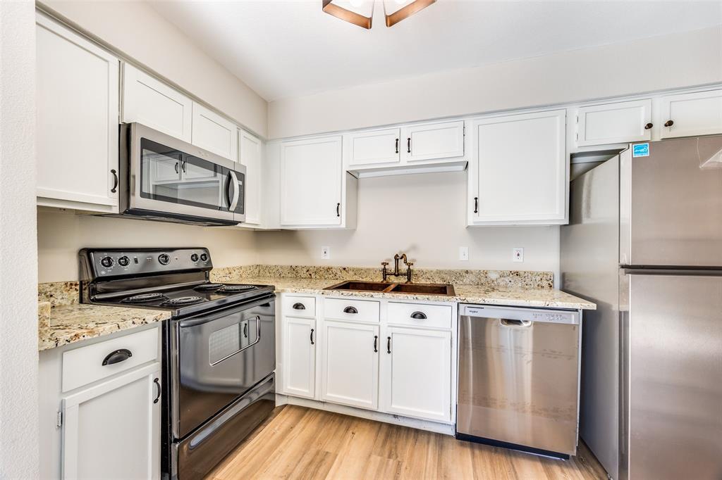 5300 Keller Springs Road, Unit 1067 Dallas, TX 75248 - Photo 10 of 14 a kitchen with granite countertop cabinets stainless steel appliances and a wooden floor
