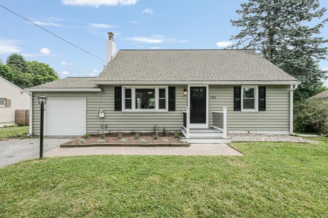 View of front of property featuring a garage and a front lawn