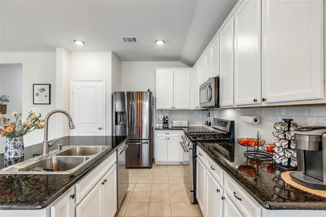 a kitchen with kitchen island granite countertop a sink stainless steel appliances and cabinets