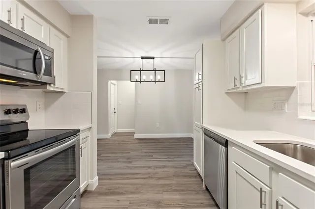 a kitchen with stainless steel appliances granite countertop a sink a stove and microwave