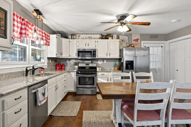a kitchen with kitchen island granite countertop a sink appliances cabinets and a counter top space
