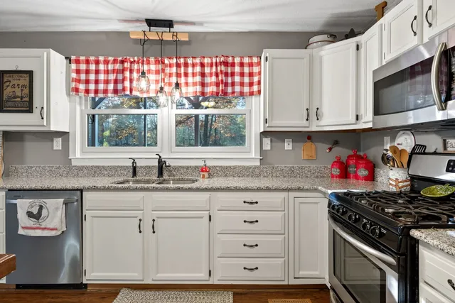 a kitchen with granite countertop white cabinets and window