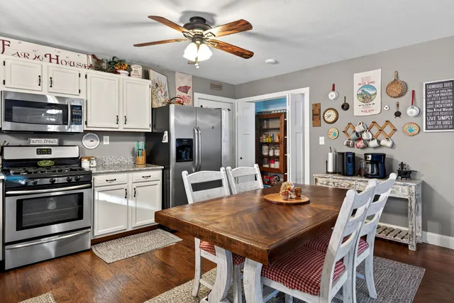 a kitchen with stainless steel appliances granite countertop a stove a refrigerator a microwave a dining table and chairs with wooden floor