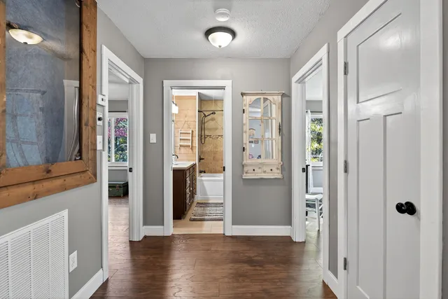 a view of a hallway with wooden floor and a bathroom