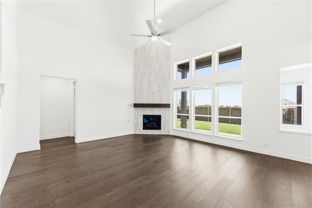 1145 Hitching Post Way Oak Point, TX 75068 - Photo 16 of 39 an empty room with wooden floor fireplace and windows
