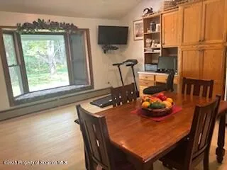 a kitchen with stainless steel appliances granite countertop a refrigerator a sink a dining table and chairs with wooden floor