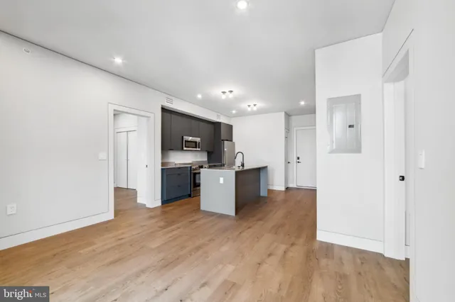a view of kitchen with kitchen island white cabinets stainless steel appliances and wooden floor
