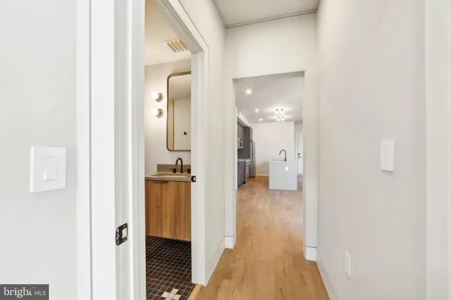 a view of a hallway with wooden floor and a bathroom