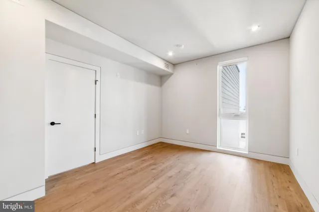 an empty room with wooden floor and windows