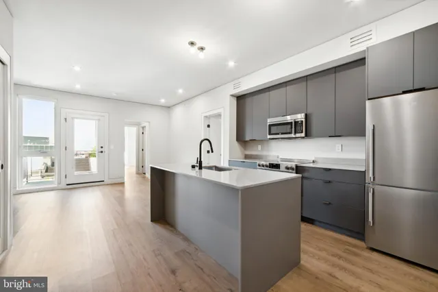 a kitchen with a refrigerator a stove top oven and wooden floors