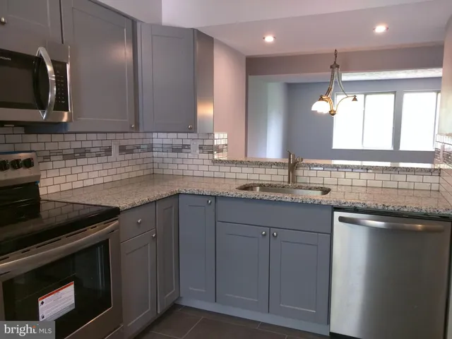 a kitchen with stainless steel appliances granite countertop a sink stove and microwave