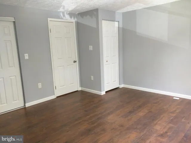 a view of an empty room with wooden floor and closet area