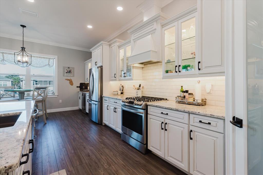 216 High Street Tarpon Springs, FL 34689 - Photo 22 of 75 a kitchen with stainless steel appliances a stove a sink a refrigerator and white cabinets with wooden floor