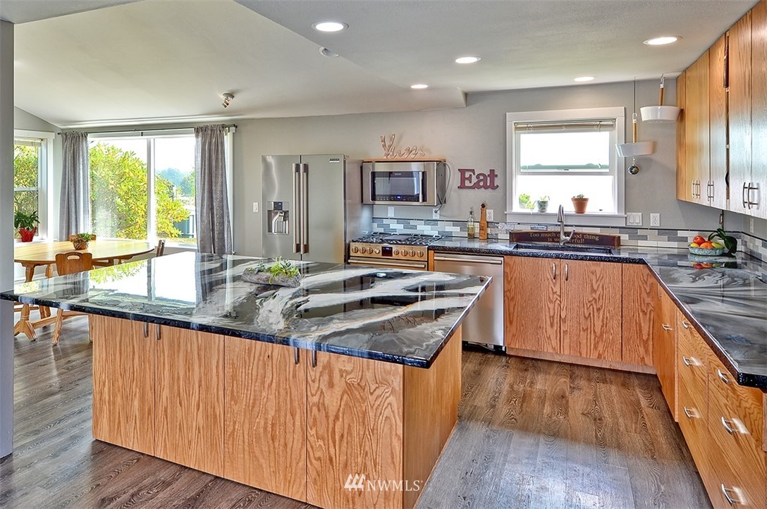2452 Douglas Road Ferndale, WA 98248 - Photo 4 of 27 a kitchen with stainless steel appliances granite countertop wooden floor sink stove and wooden cabinets