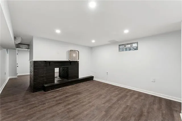 a view of an empty room with wooden floor and a fireplace
