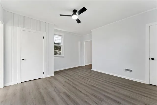 an empty room with wooden floor ceiling fan and windows