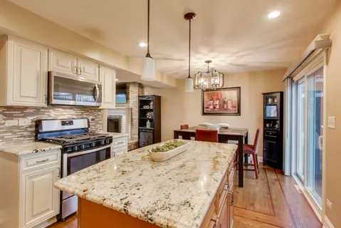 a kitchen with stainless steel appliances kitchen island granite countertop a stove a refrigerator a kitchen island a cabinets and a wooden floor