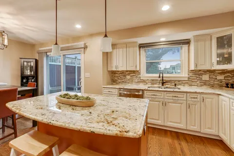 a kitchen with granite countertop a sink cabinets and wooden floor