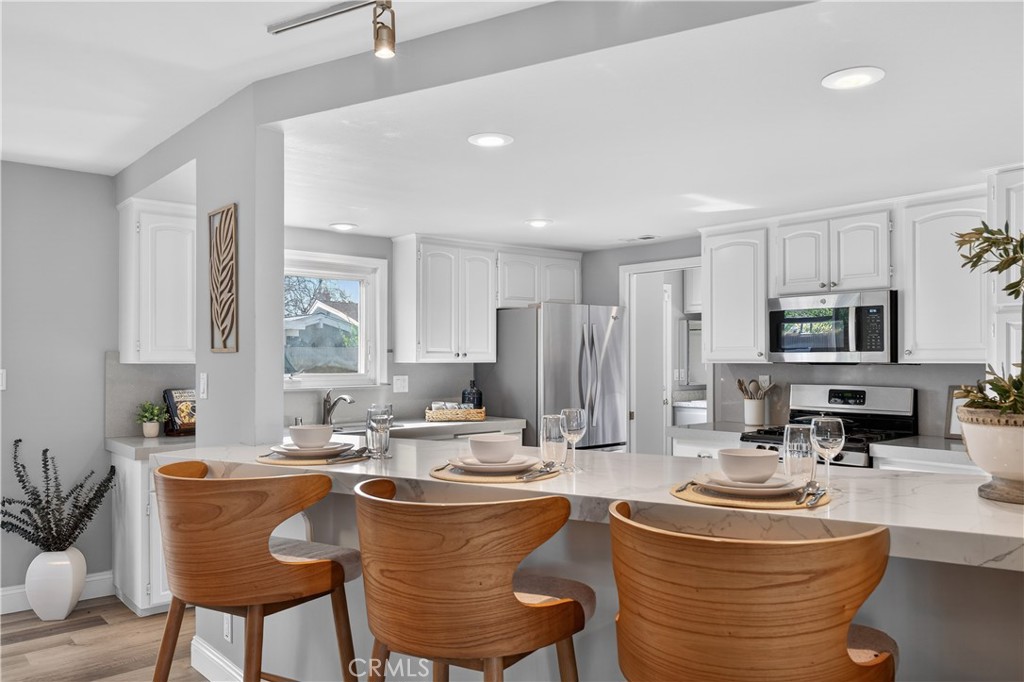 1610 East 20th Street Santa Ana, CA 92705 - Photo 10 of 43 a dining room with stainless steel appliances kitchen island granite countertop a sink a stove a dining table and chairs