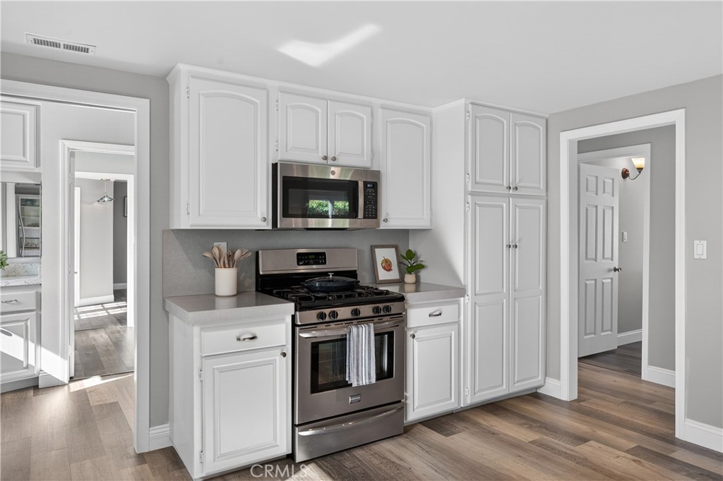 1610 East 20th Street Santa Ana, CA 92705 - Photo 13 of 43 a kitchen with white cabinets and stainless steel appliances