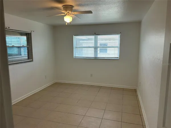an empty room with windows and fan