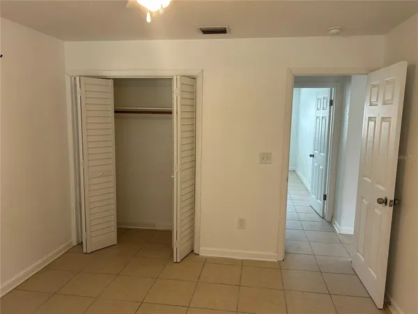 a view of an empty room with closet and mirror
