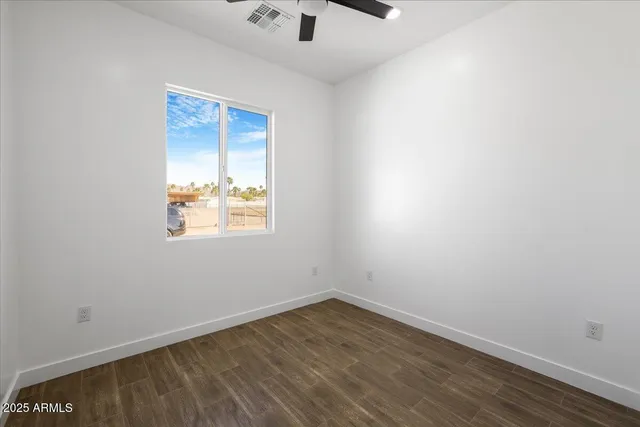 a view of an empty room with closet and wooden floor