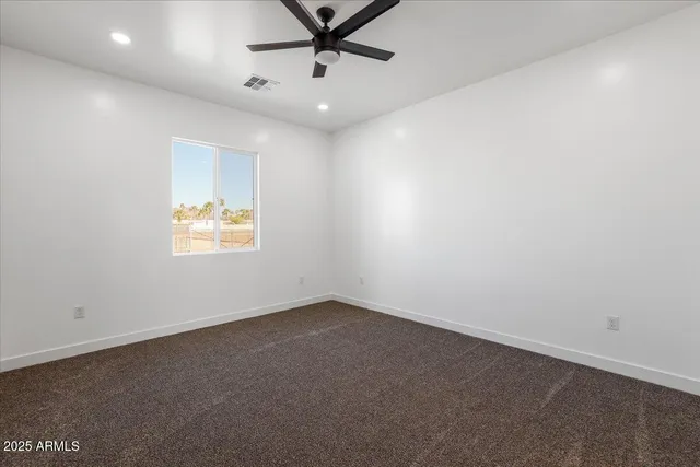 en empty room with ceiling fan and window