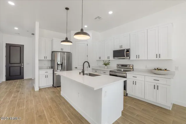 a kitchen with stainless steel appliances kitchen island a sink a refrigerator and cabinets