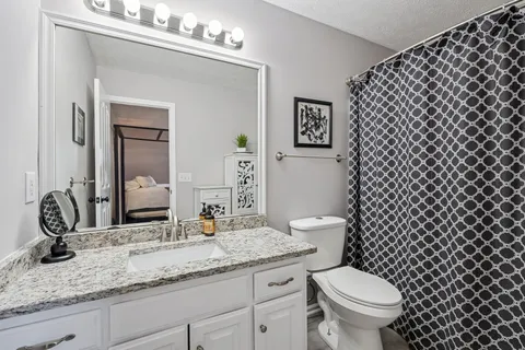 a bathroom with a granite countertop toilet a sink and a mirror