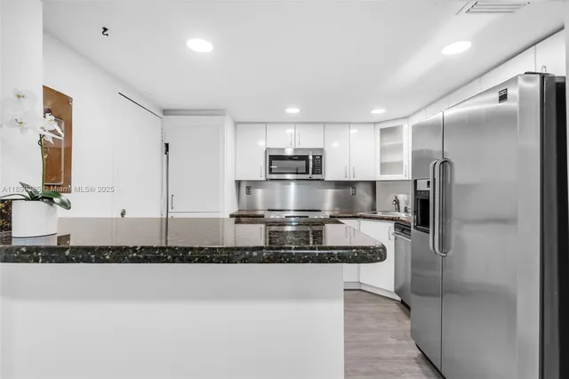 a modern kitchen with stainless steel appliances granite countertop a refrigerator and a sink