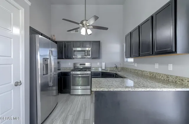 a kitchen with granite countertop stainless steel appliances a sink cabinets and wooden floor