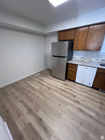 556 North Fairfield Road, Unit D4 Layton, UT 84041 - Photo 13 of 23 Kitchen featuring dishwasher, freestanding refrigerator, light wood-type flooring, light stone counters, and brown cabinetry