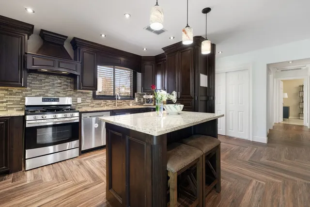 a kitchen with a stove kitchen island a sink dishwasher a dining table and chairs with wooden floor