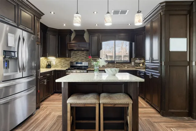 a kitchen with kitchen island granite countertop a sink cabinets and stainless steel appliances