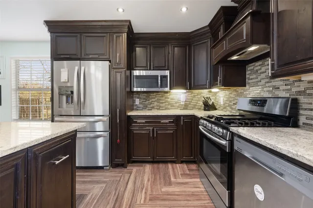 a kitchen with stainless steel appliances granite countertop wooden cabinets stove top oven and sink